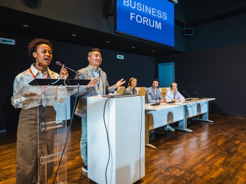 Asian and African American business people having speach on a press conference in a convention center. Business forum